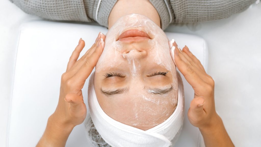Top view on a pretty woman face during massaging skin with cream