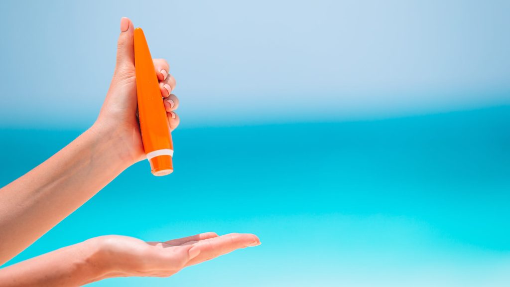 Woman hand holding a suncream on beach