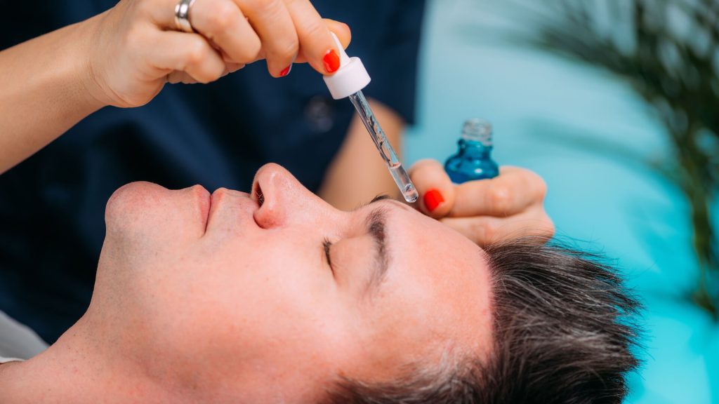 Cosmetician Applying Hyaluronic Acid Serum on Man’s Face