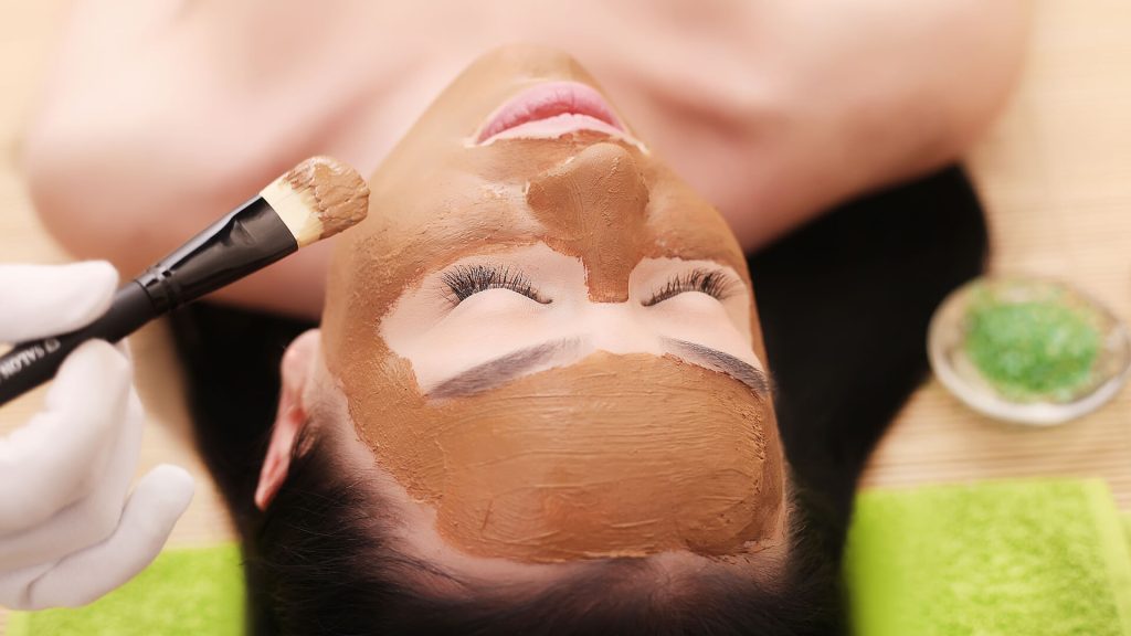 Woman getting a facial mask in spa